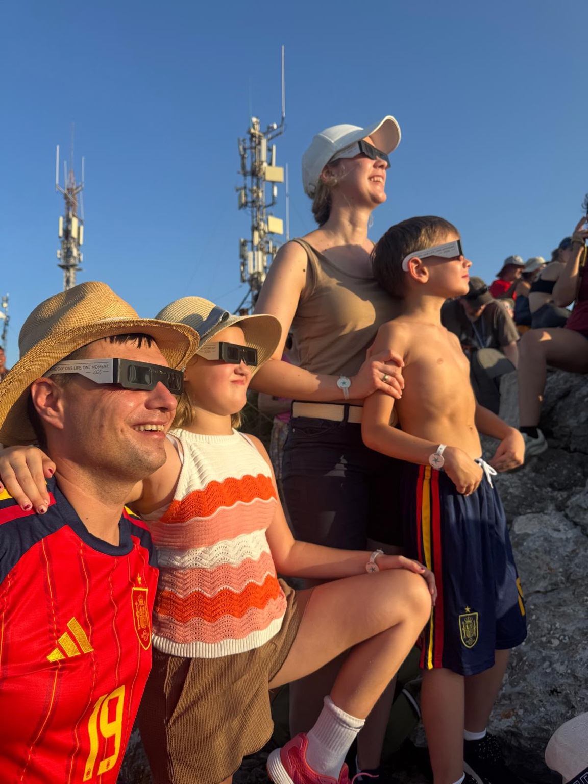Eine Familie schaut gemeinsam mit Sonnenfinsternisbrillen in den Himmel.
